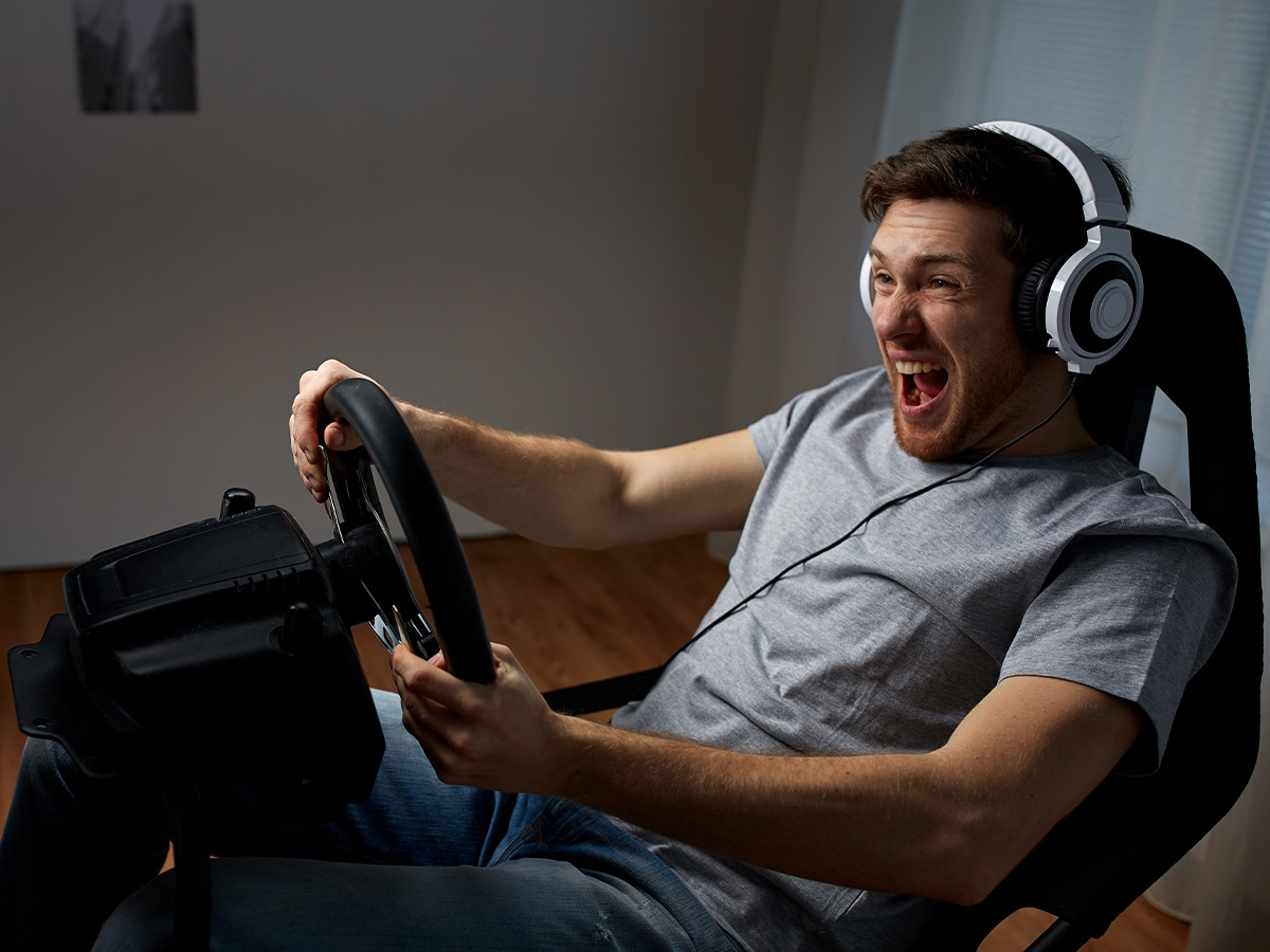 Image of a man wearing headphones playing a racing video game