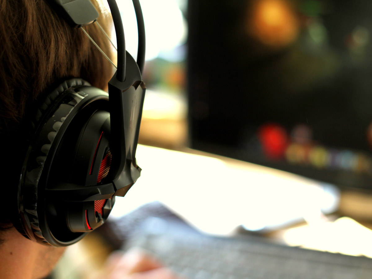 Close up on someone wearing a headset and looking at a PC monitor