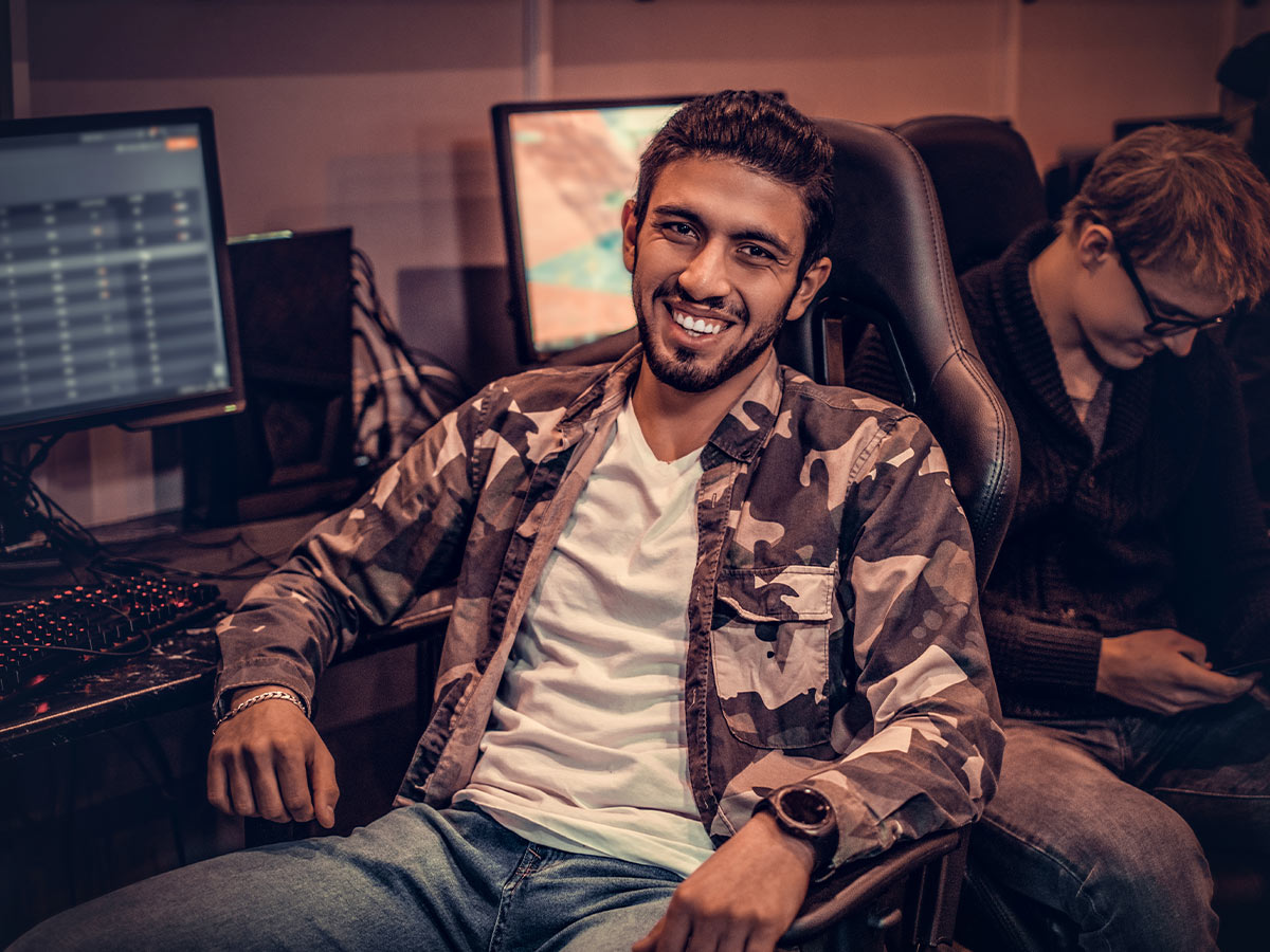  Image of a man smiling and sitting in a gaming chair in front of a computer